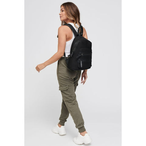 model in green cargo pants carrying a sleek black backpack