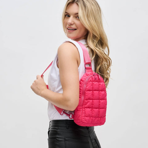 a model carrying a bright pink puffer sling backpack