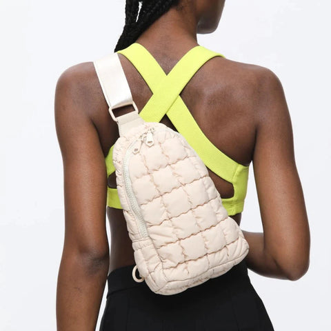 a model in workout clothes carrying a light pink puffer sling bag