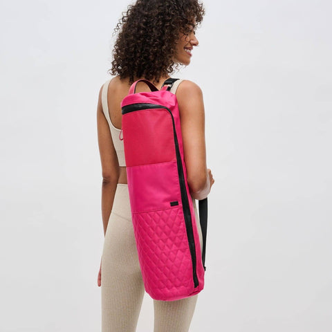 a model carrying a bright pink yoga mat bag