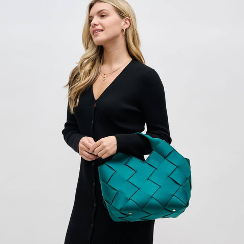 a model in black carrying a teal woven handbag