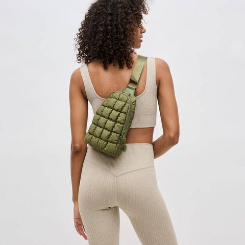 a model in an activewear set carrying a green crossbody bag