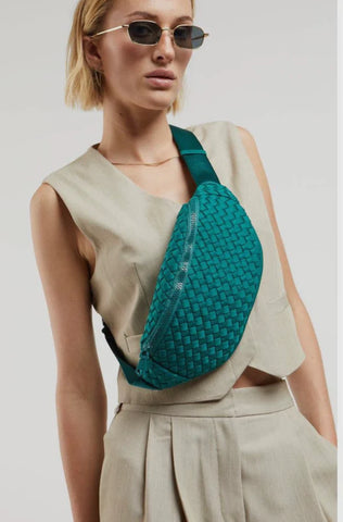 a model in beige wearing a green belt bag across her chest