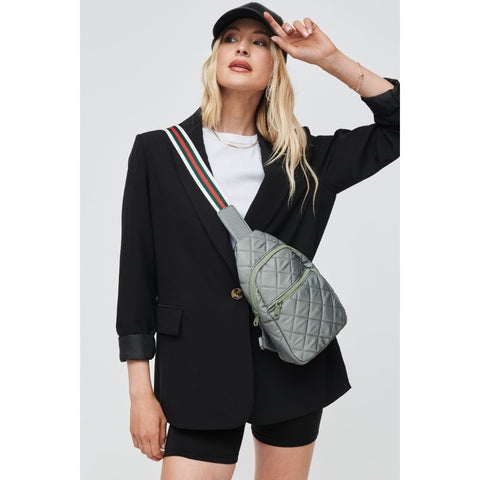 a model in a black blazer wearing a gray and striped sling backpack