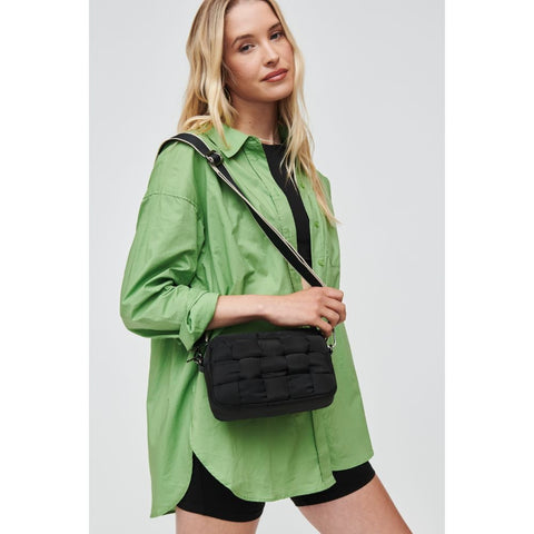 a model in a green shirt carrying a black woven crossbody bag