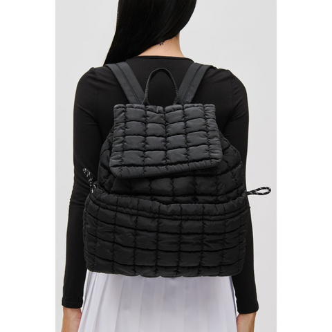 a model wearing a black quilted puffer backpack