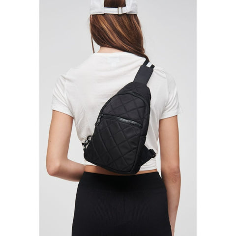 a model wearing a black sling backpack in a quilted fabric
