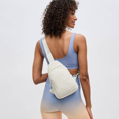 a model in activewear wearing a cream sling backpack
