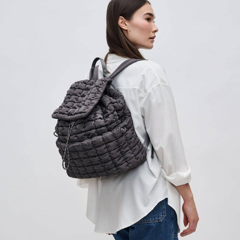 a model in a white shirt wearing a gray puffer backpack
