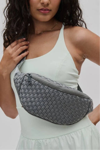 a model wearing a grey woven belt bag