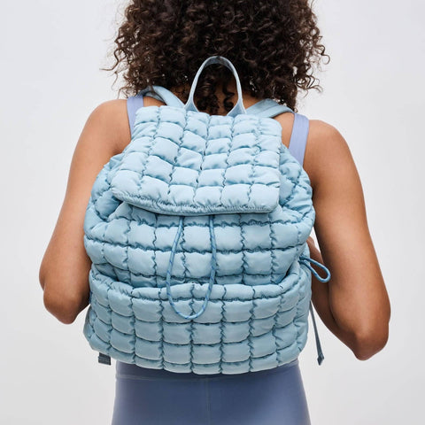 a model wearing a light blue puffer backpack