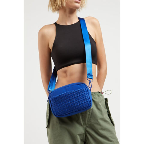 model wearing a royal blue crossbody bag in a woven neoprene material