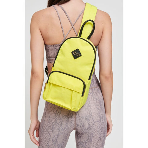model wearing a yellow sling backpack with black accents
