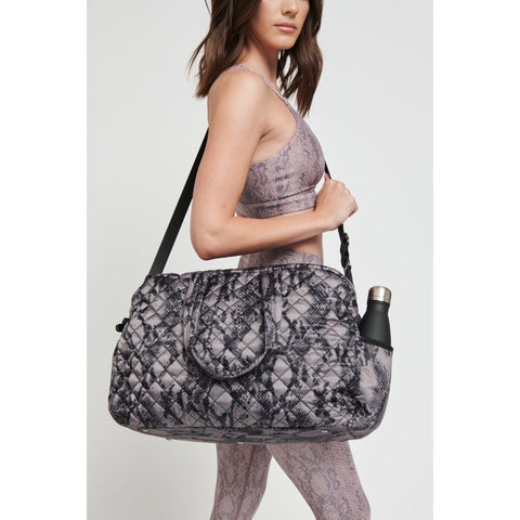 model holding a black and gray patterned weekender bag