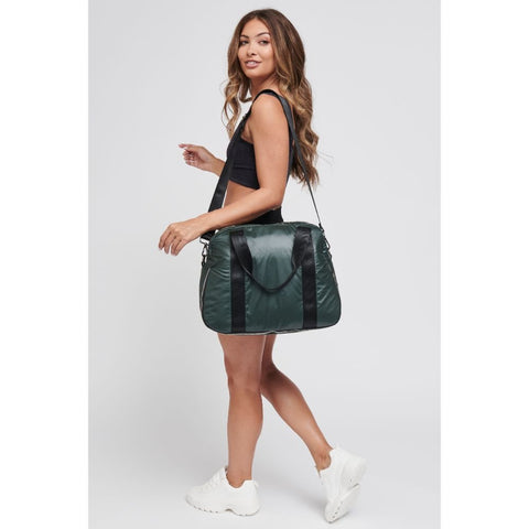 a model carrying a black and green duffel bag in a shiny material