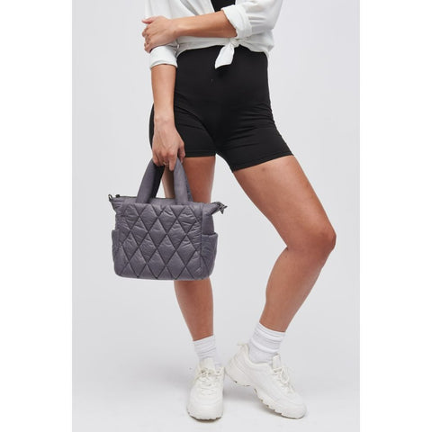 a model holding Sol and Selene’s small puffer mini tote in gray 