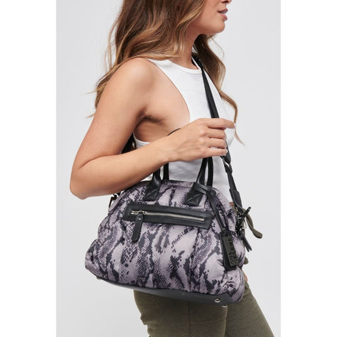 a model carrying a purple and black snake print mini satchel