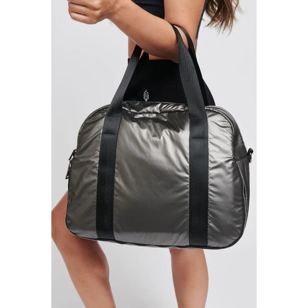 woman carrying a gray, reflective duffel bag