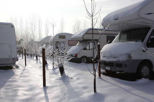 A row of RVs parked and winterized for the winter season.