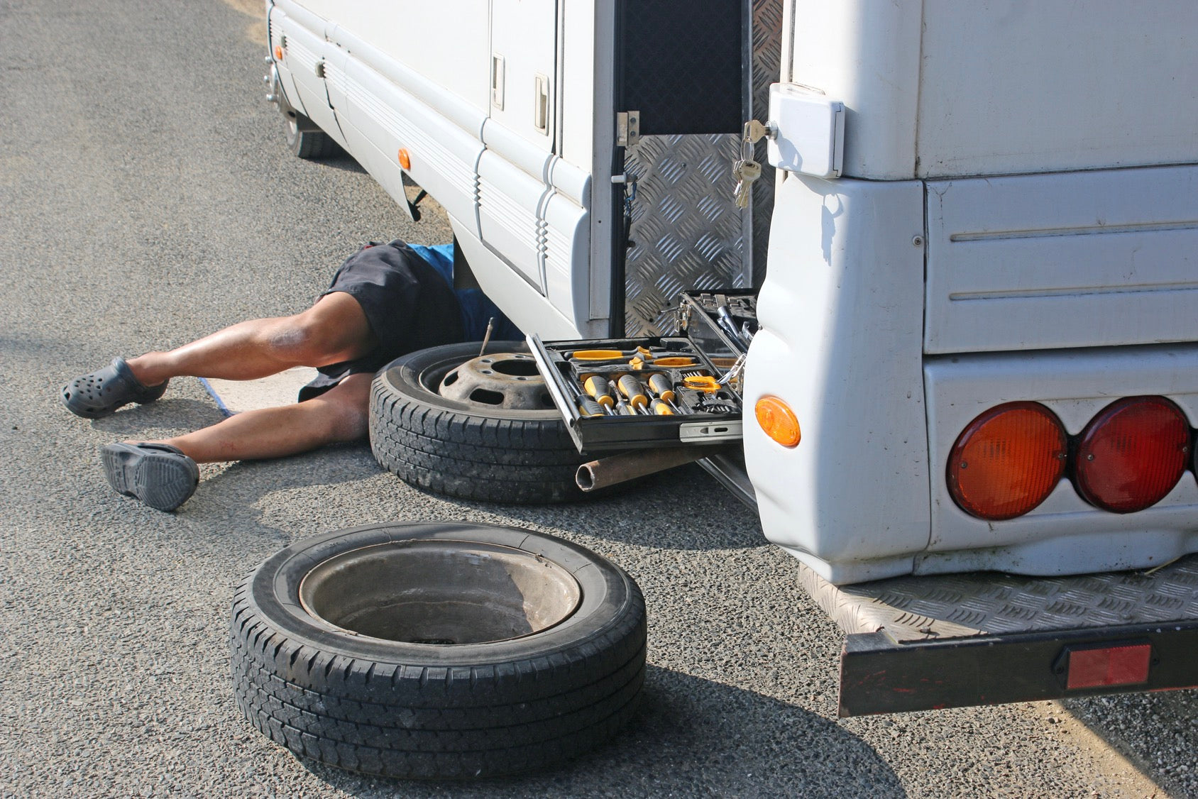 Man under recreational vehicle changing tire