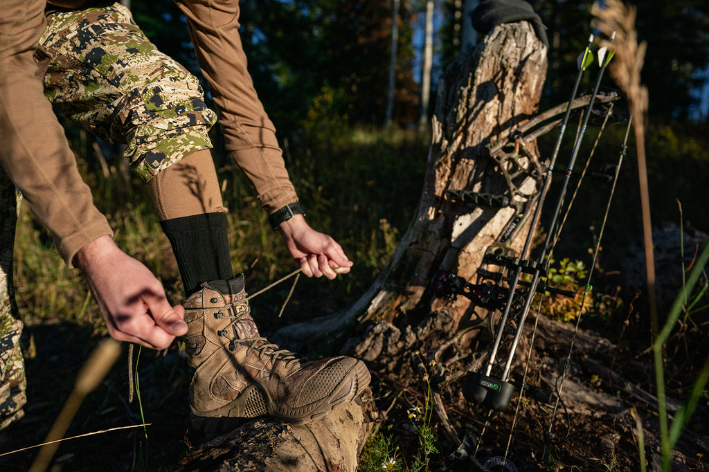 hunter tying boots with bow in background