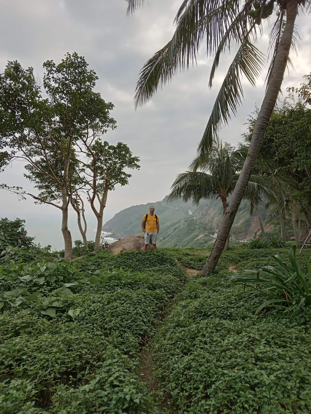 A man stands on top of 'Monkey Mountain' in Vietnam, with a beautiful coastal view behind him