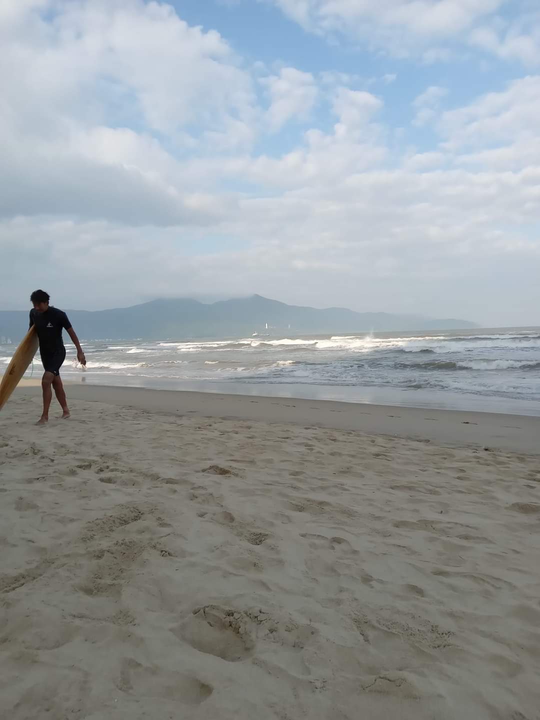 A surfer walks along the sand of Da Nang Beach in Vietnam