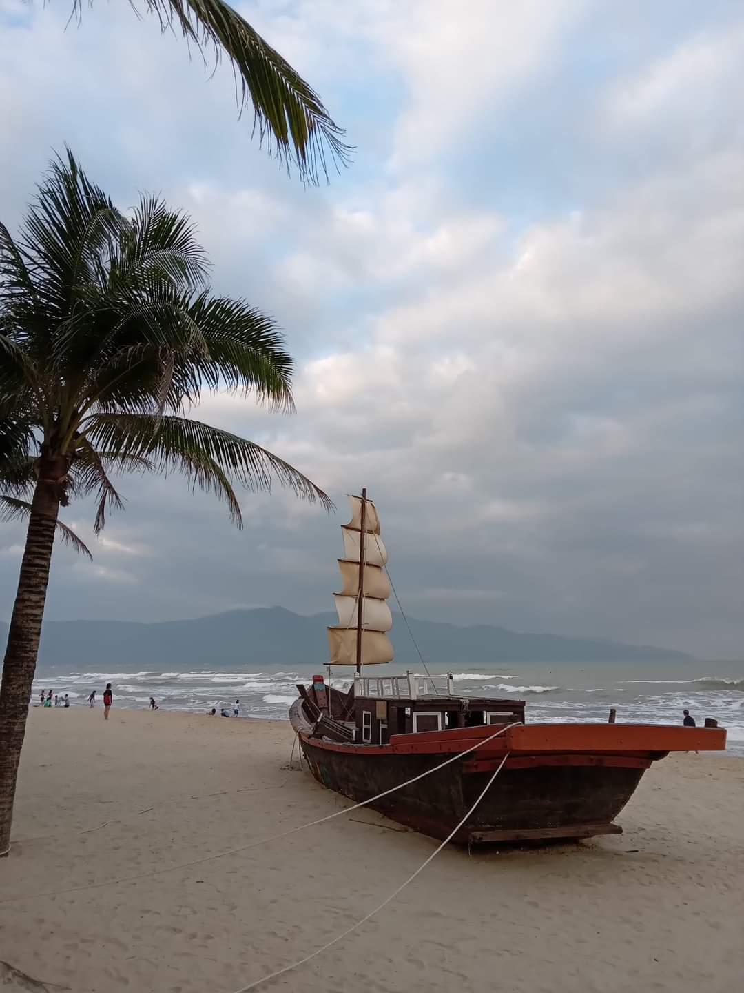 Pirate ship on Da Nang beach in Vietnam, palm tree in the foreground and ocean in the background