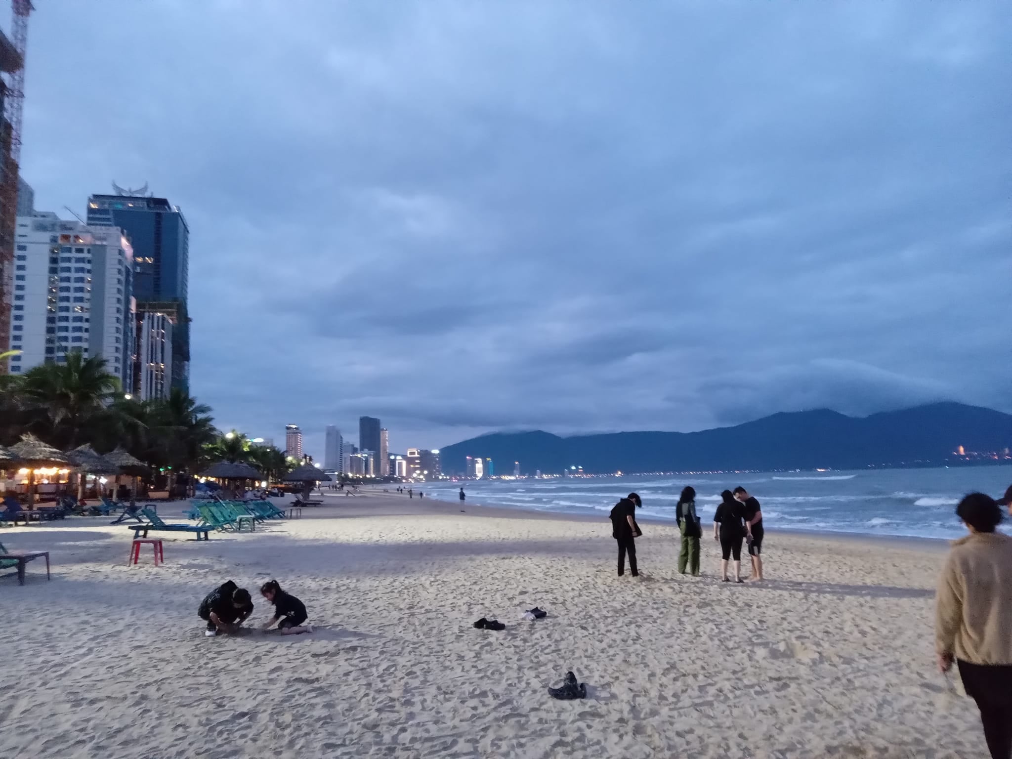 People sitting on the sand watching the sunset on the beach in Da Nang Vietnam