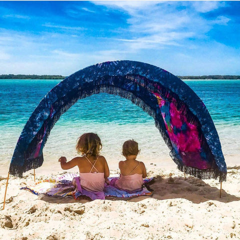 two little girls sitting beneath an arched Suniela Beach shade