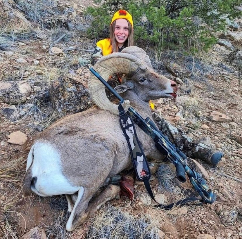 Young girl proudly posing with her prize buck after a successful hunt, showcasing her youth model rifle with scope