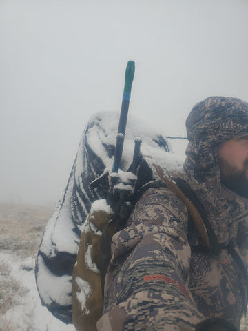 Hunter in camo with snow-covered rifle, testing shooting accuracy