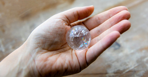 Clear quartz crystal ball on a hand