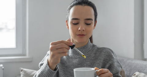 Woman drinks tea with drops of cajeput oil for stress relief