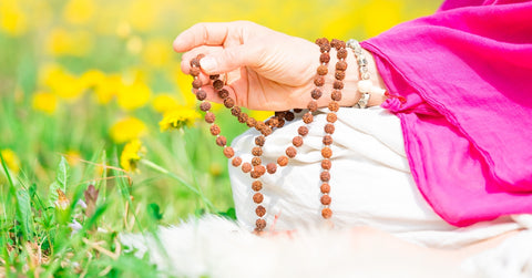 woman using mala beads on meditation