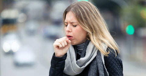 young woman coughing in the street