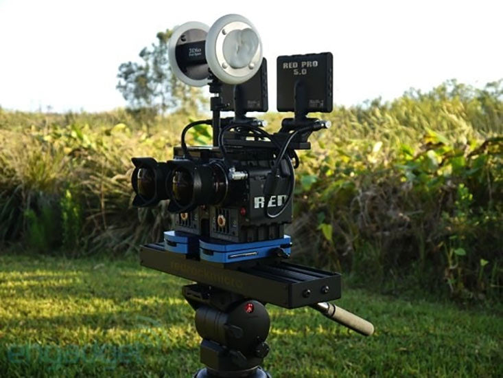 Image of a custom VR capturing rig, including two RED cameras and a 3Dio binaural microphone mounted on a tripod with a corn field in the background.