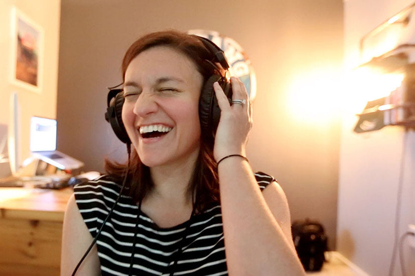 Image of a woman laughing while wearing headphones.
