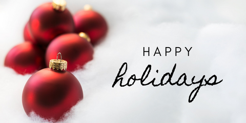 Red holiday decorations on a bed or snow with Happy Holidays text