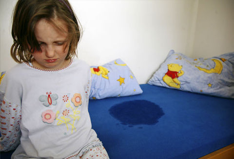 Sad child standing by wet bed sheets