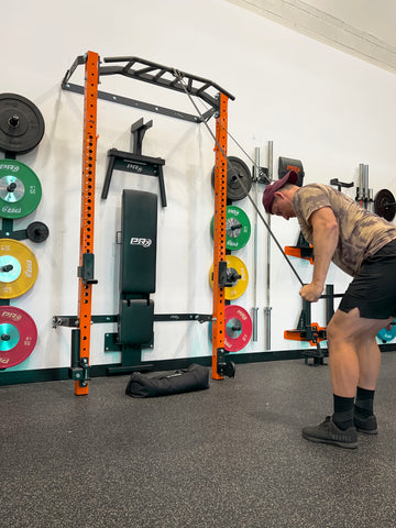 Man performing Bent Over Lat Pull using a mobility band on a PRx Performance Folding Squat Rack