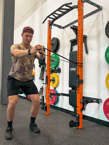 Man performing Pallof Press using mobility band on PRx Performance Folding Squat Rack