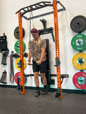 Man using mobility band on PRx Performance Folding Squat Rack to perform Tricep Extensions