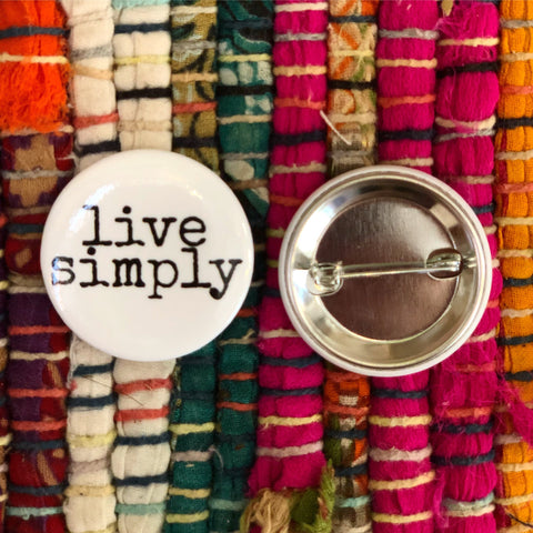 live simply on a campaign pin on a colorful rug