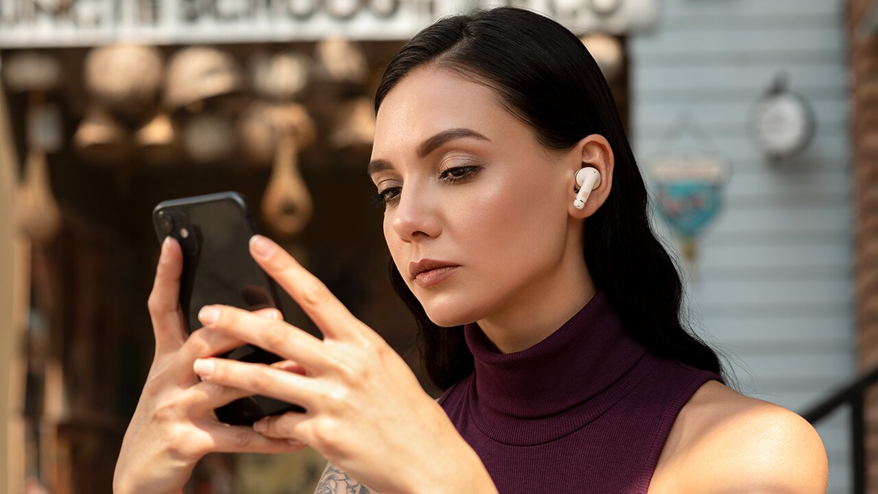 girl using active noise cancelling true wireless earbuds in cafe