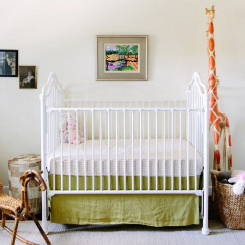 Traditional cot with green linen crib skirt