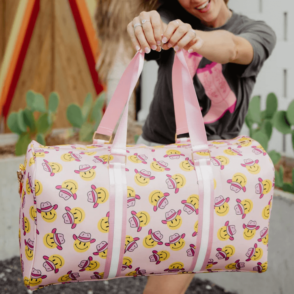 A woman holding a cowgirl-themed weekender bag