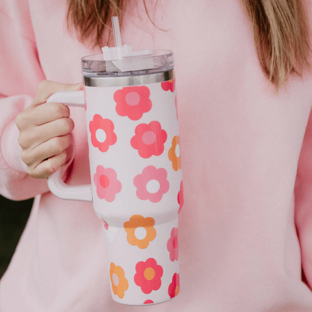 A woman holding a stainless steel tumbler cup with a flower print