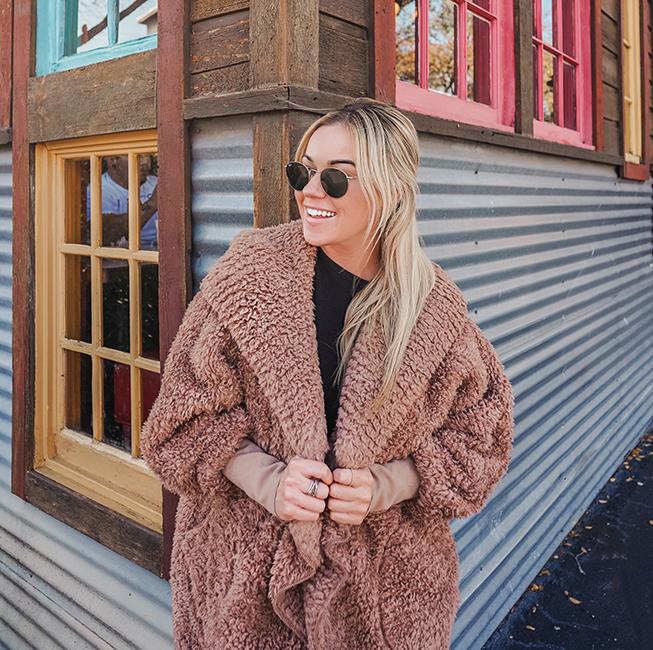 woman in tan sherpa body wrap and sunglasses