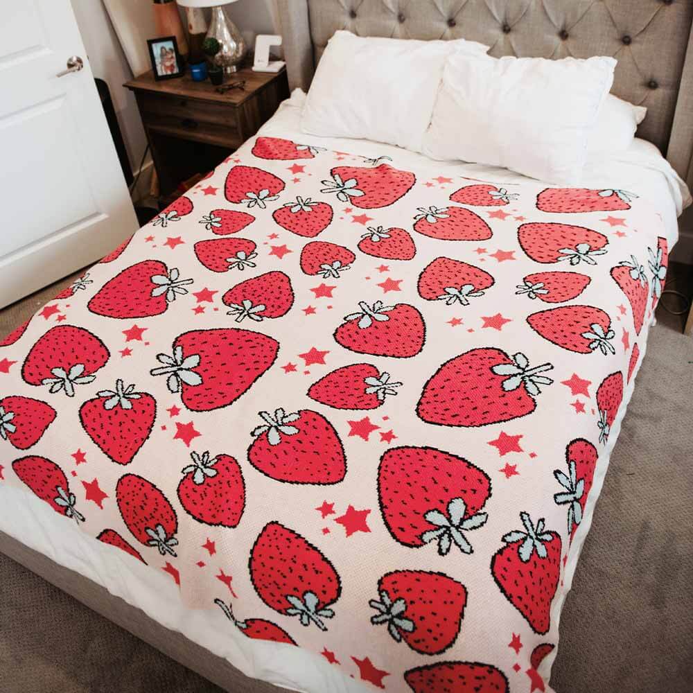 A strawberry-printed oversized knitted blanket